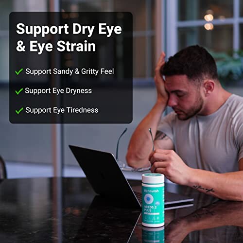 Man with dry eyes using laptop and holding eye supplement.