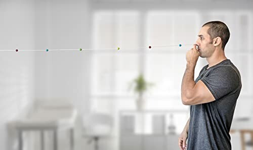 Man blowing on a string with colorful beads indoors